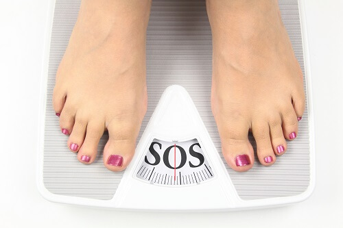 Person weighing themselves on scales
