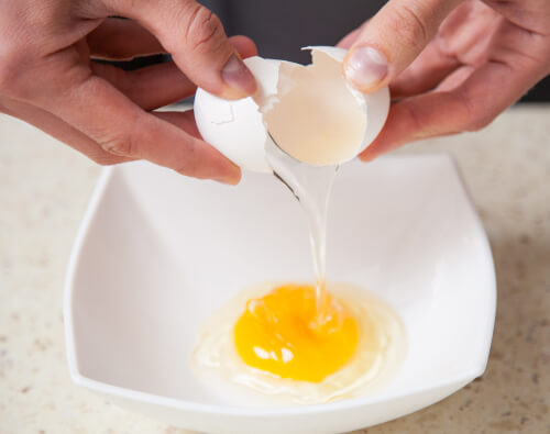 Man breaking egg into bowl
