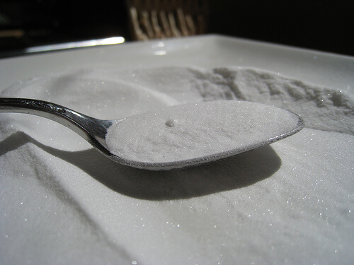Baking soda being lifted with a spoon.