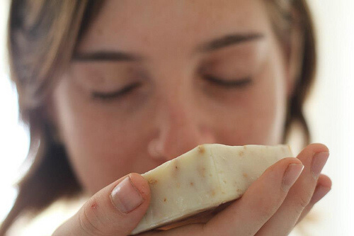A woman smelling a bar of soap.