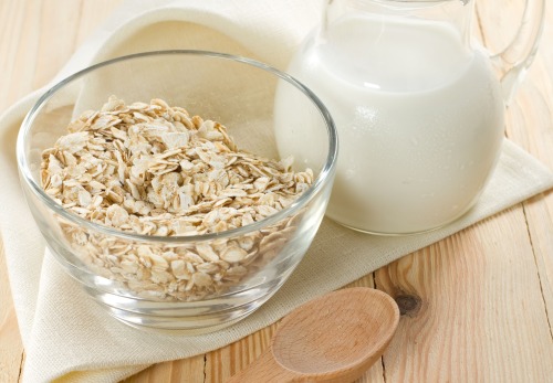 A bowl of oats next to a glass of oatmeal water