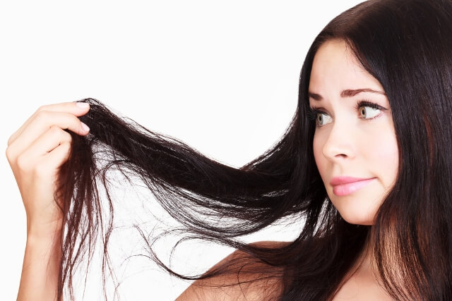 Girl looking at dry ends in hair