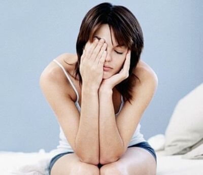 Tired woman sitting on the side of the bed