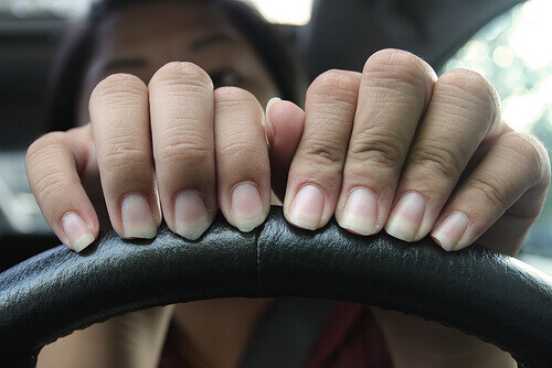 Woman with hands on steering wheel really needs a manicure nails peel long and uneven nails