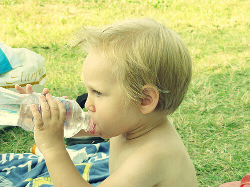 Small boy drinking water while eating