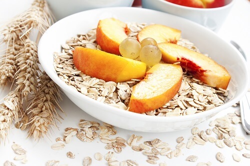 A bowl of oats with grapes and peaches