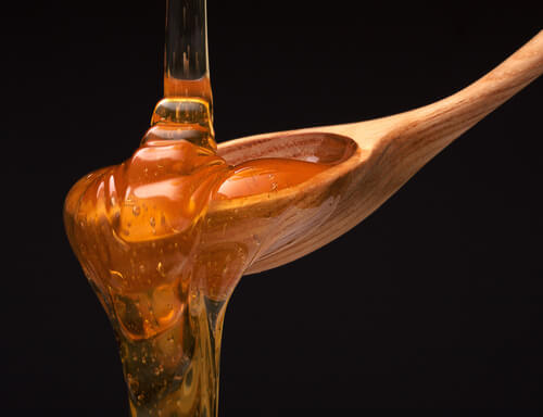 Honey pouring over a wooden spoon