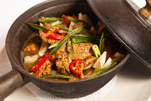 A pan with chicken and vegetables.