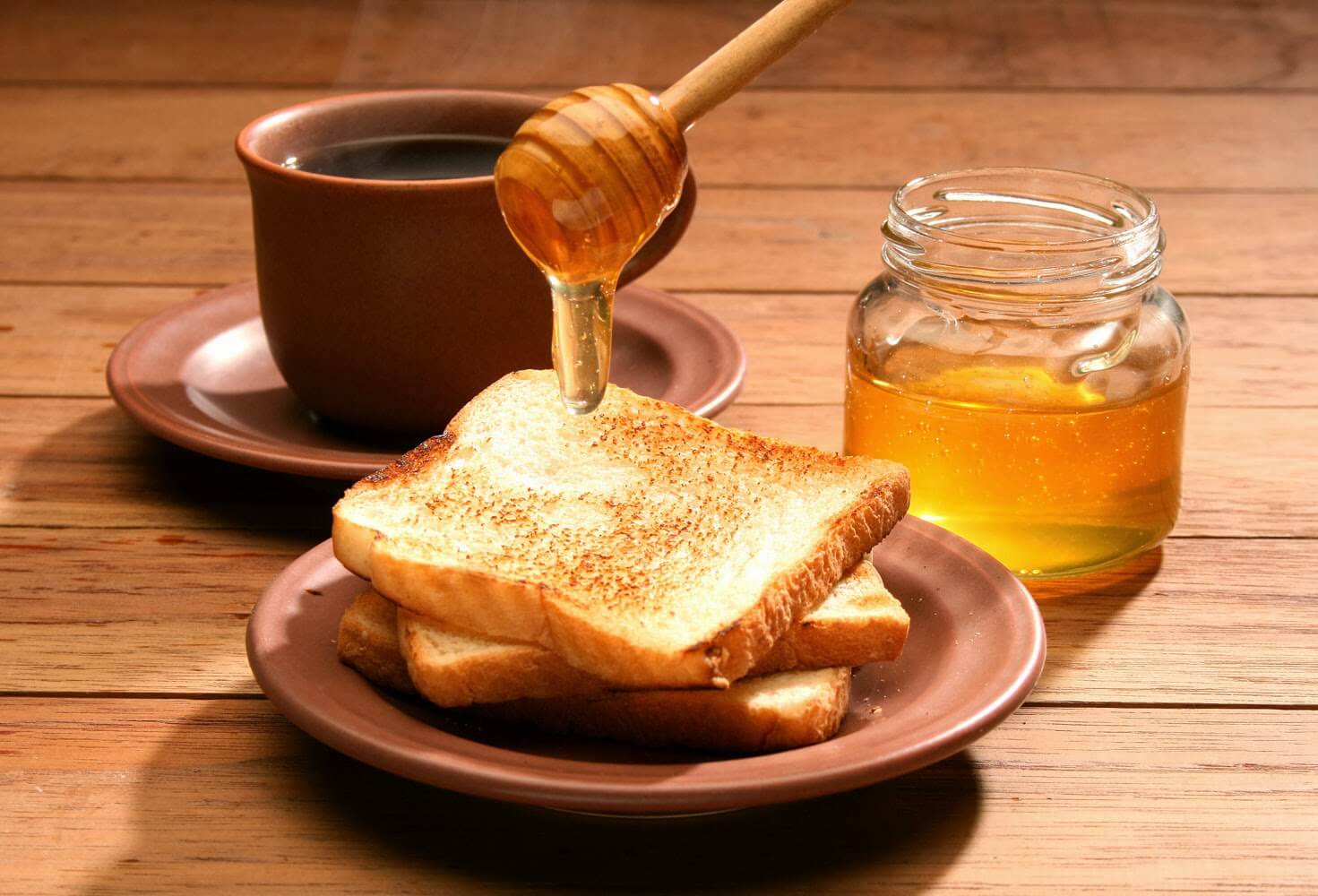 Pouring some honey on a toast.
