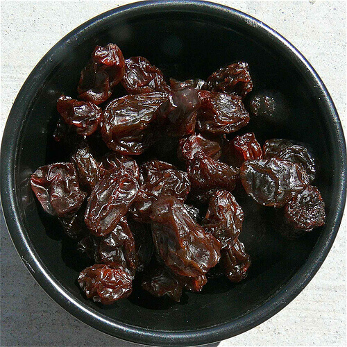 Raisins in a black colored bowl white background benefits of raisins