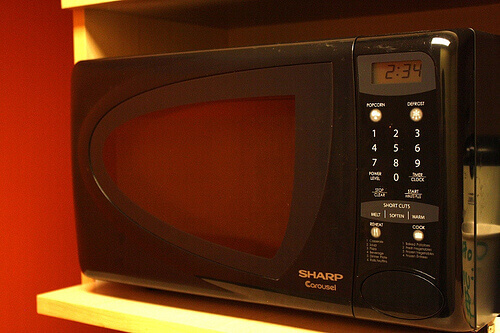 Black microwave on a white shelf
