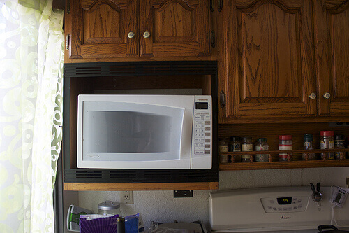White microwave with wood cupboards