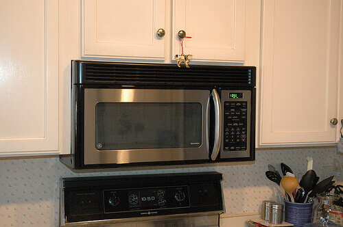 Stainless steel microwave with white cupboards