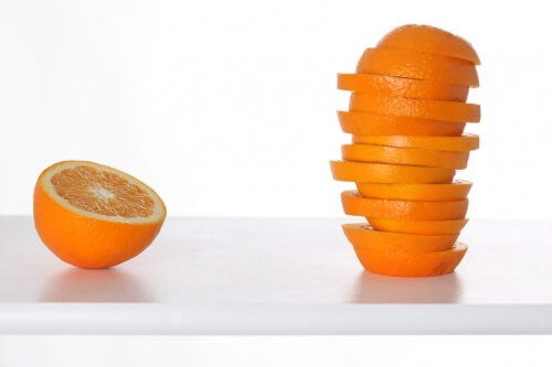 Half an orange next to stack of slices