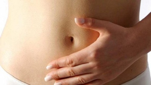 Woman clutching bloated stomach indicators of liver problems