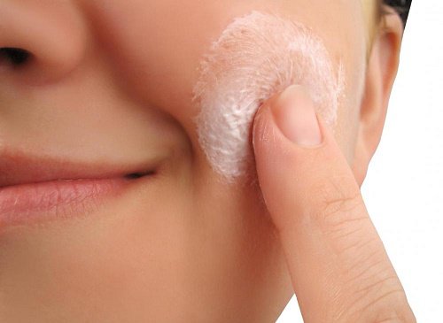 Lady applying cream to face
