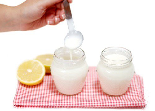 Two jars of yogurt with lemon beside them.