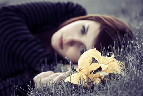 depressed woman looking at a flower
