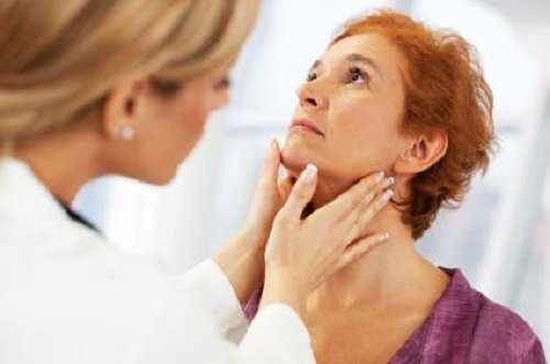 A doctor checking the thyroid of a woman.