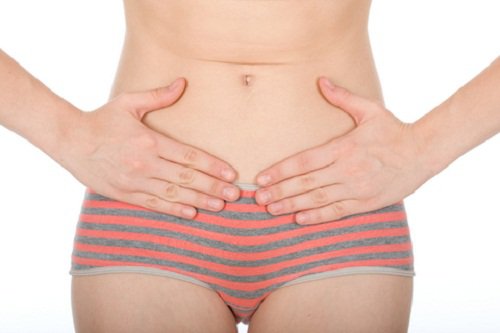A woman in her panties holding her stomach.