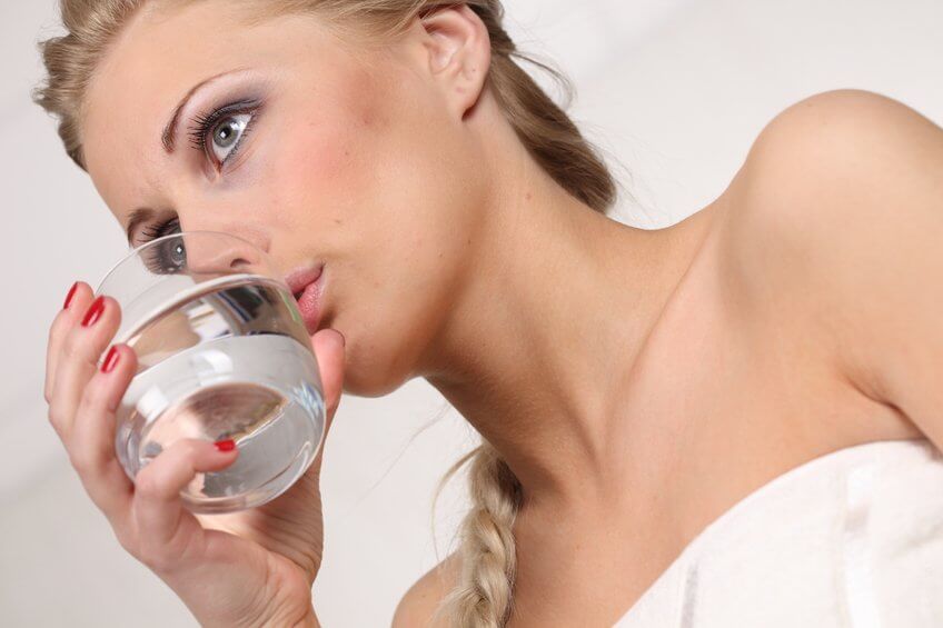 woman drinking a glass of baking soda and lemon