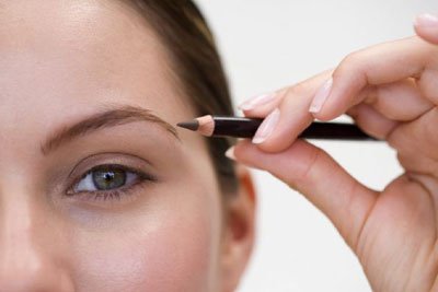 Woman defining her eyebrows with a pencil