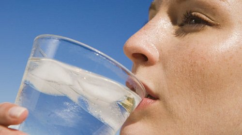 Lady drinking a glass of water with ice