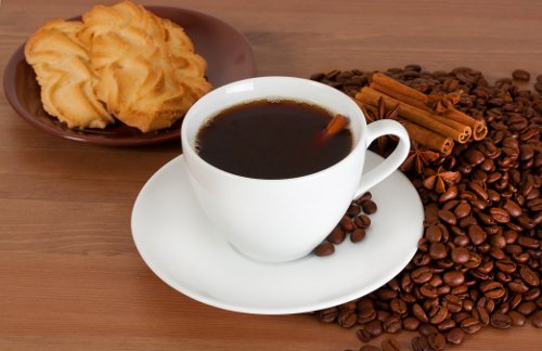Cup of coffee, cookies, coffee grounds, and cinnamon sticks