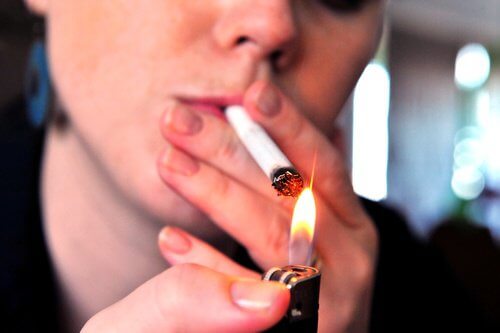 A woman lighting a cigarette.