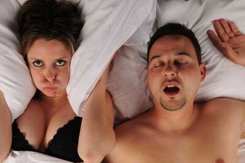 A man snoring in bed next to a woman.