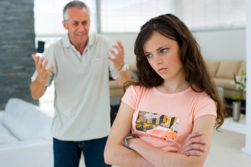 Teenage girl arms crossed moody and upset father complaining in background educate your teenager
