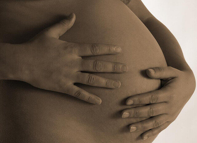 Schwangere Frau fasst sich an den Bauch