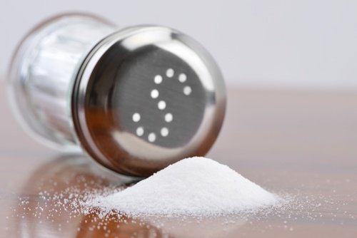 Tipped over salt shaker with spilled salt
