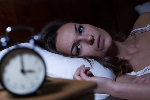 Woman staring at an alarm clock. not able to sleep