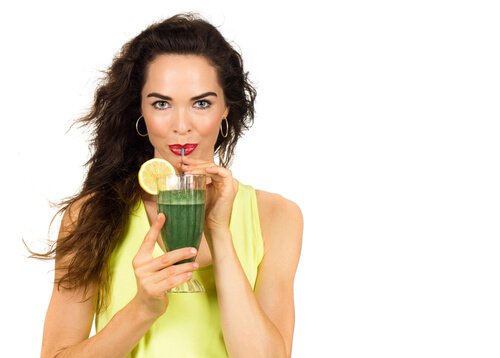 Woman drinking a green juice to strengthen her veins