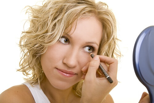 A woman applying eyeliner on herself.