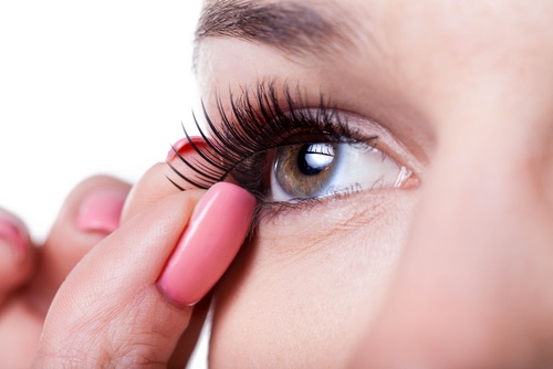 A woman adjusting a fake eyelash.