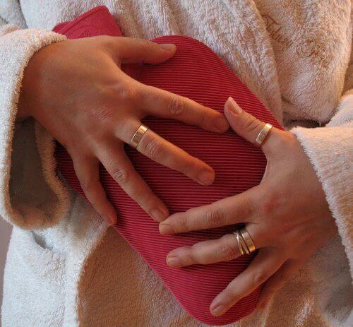 Woman holding a heating pad to her lower abdomen pain during menstruation