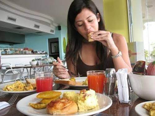 A woman overeating and eating many unhealthy foods