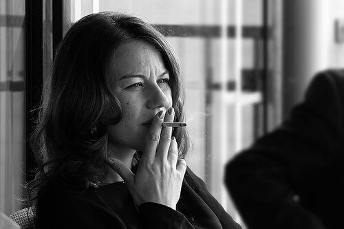 Black and white photo woman smoking cigarette pain during menstruation