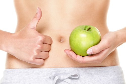 Holding an apple next to a flat belly