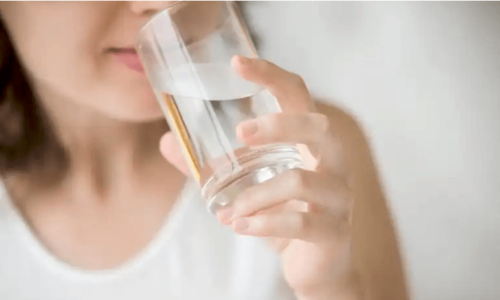 A woman drinking water to balance her body's pH.