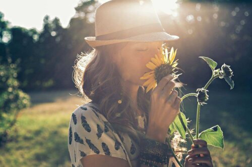 A woman smelling a sunflower.
