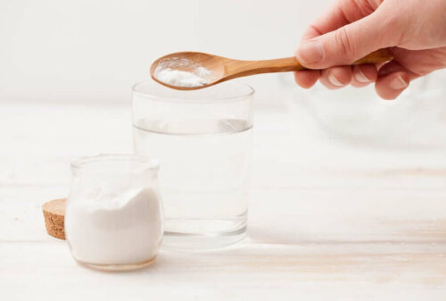 A person putting baking soda into a glass of water.