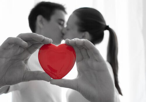 couple holding a red heart and kissing