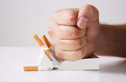 A hand crushing a box of cigarettes.
