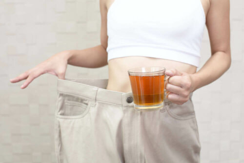 A woman with a cup of tea that serves to burn fat and reduce abdominal bloating.
