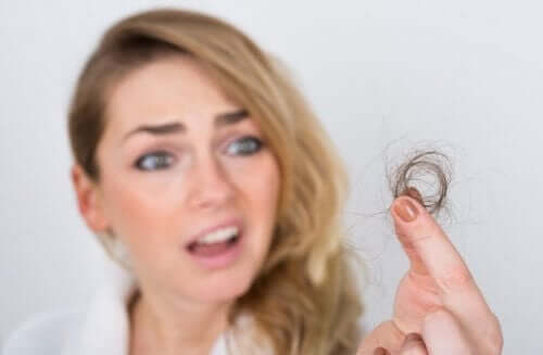 A woman looking at her broken hair.