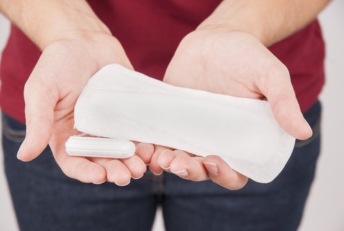 woman holding a tampon and a pad