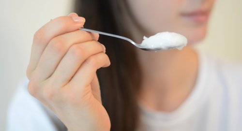 Woman's hand holding spoonful of coconut oil
